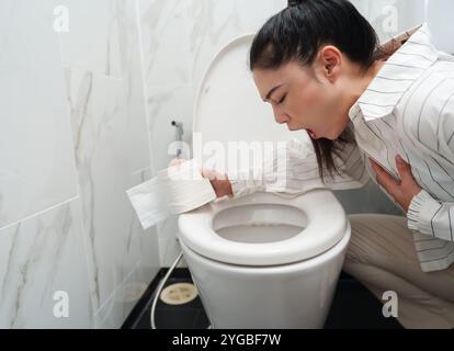 donna che vomita nella ciotola del bagno Foto Stock