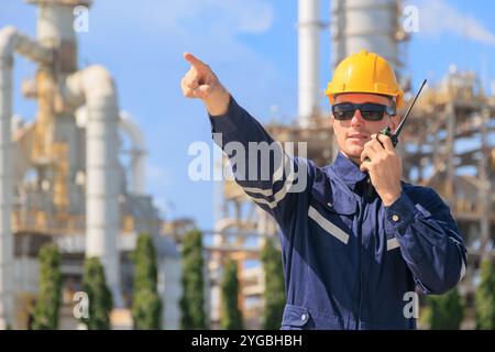 Ingegnere del settore petrolifero che lavora all'aperto. Il controllo del team di assistenza per petrolio e gas degli impianti di raffineria gestisce la parte anteriore di manutenzione di grandi tubazioni di gas complesse Foto Stock