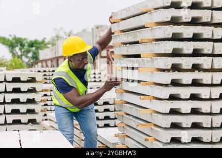 Africano nero lavoratore maschio che lavora in calcestruzzo prefabbricato fabbrica controllare la produzione di qualità presso il sito. Foto Stock