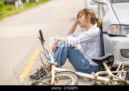 Le donne che guidano l'auto seduto si sentono in colpa davanti alla strada in attesa della polizia dopo che l'incidente ha colpito il ciclista in autostrada Foto Stock