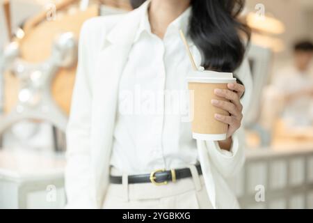 Le persone che lavorano da vicino gestiscono la tazza di caffè caldo di carta, risparmiando l'ambiente utilizzando il concetto di contenitore per bevande riciclate. Foto Stock