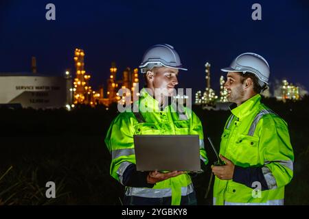 Tecnico del turno di notte addetto all'assistenza alle raffinerie di petrolio e gas lavora sodo negli impianti dell'industria petrolifera sfondo sfocato chiaro. Foto Stock