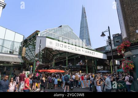 Turisti e visitatori che affollano lo storico Borough Market, un mercato alimentare all'ingrosso nel centro di Londra, con lo Shard sullo sfondo. Inghilterra Foto Stock