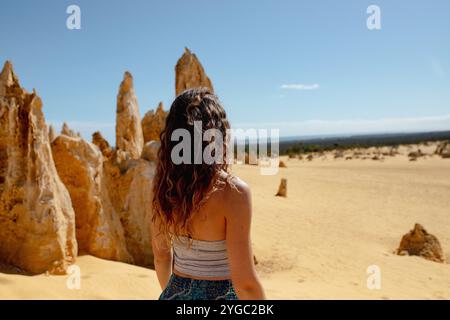 Un giovane turista brunetta abbronzato che guarda il paesaggio dei pinnacoli in pietra calcarea dorata dell'Australia Occidentale. Foto Stock