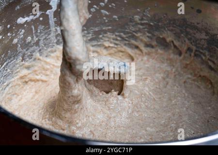 Impastare l'impasto elastico per il pane in una macchina per impastare in una panetteria, primo piano. Miscelatore per impastare. Impastare impasti senza lievito da chicchi interi e. Foto Stock