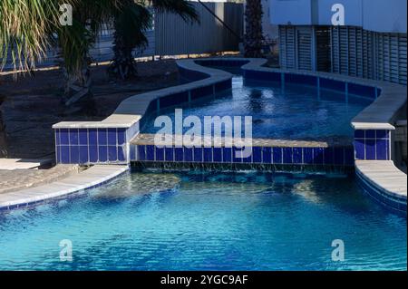 Una tranquilla piscina si snoda attraverso un paesaggio soleggiato, scintillante di riflessi blu e vegetazione. Foto Stock