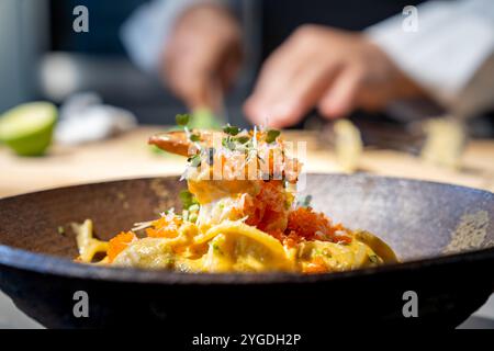 Spaghetti pasta alla carbonara uovo e formaggio cremosa salsa di panna con gamberi e micro aromi decorati sulla parte superiore della ciotola circolare in terracotta in studio Foto Stock