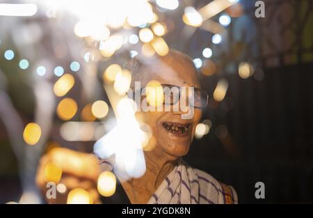 Una donna anziana di Pramod Talukdar Memorial Old Age Home brucia crackersas sparkler celebra Diwali, a Guwahati, in India il 1° novembre 2024. Diwali Foto Stock