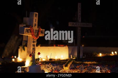 Le persone della comunità cristiana accendono candele e pregano sulla tomba del loro parente durante l'osservazione di tutte le anime, a Guwahati, Indi Foto Stock