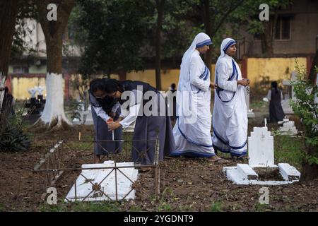 Le suore pregano sulla tomba durante l'osservazione di tutte le anime, a Guwahati, in India, il 2 novembre 2024. All Souls' Day è una festa cristiana Foto Stock