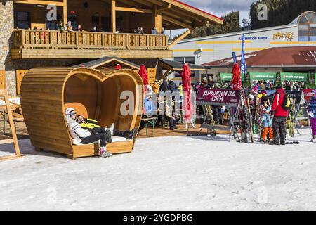 Bansko, Bulgaria, 12 dicembre 2015: Stazione sciistica bulgara, panchina a forma di cuore, gente che cammina e scia, Europa Foto Stock