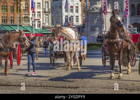 Bruges, Belgio, 10 aprile 2016: Carrozza trainata da cavalli sulla piazza del mercato nella popolare destinazione belga Bruges, Europa Foto Stock