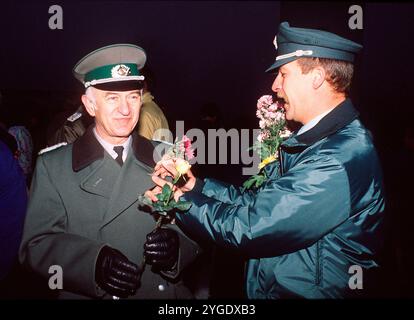 FOTO D'ARCHIVIO: 35 anni fa, il 9 novembre 1989, il muro di Berlino, il confine di pietra tra Oriente e Occidente, cadde. Un agente di polizia di Berlino Ovest (a destra) mette un fiore nell'asola del suo collega della DDR. Ritratto del busto. Formato orizzontale. ? Foto Stock