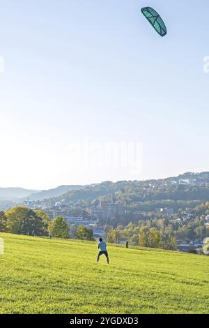 L'uomo sta guidando il kite grande su un prato verde Foto Stock