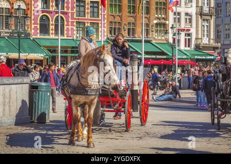 Bruges, Belgio, 10 aprile 2016: Carrozza trainata da cavalli sulla piazza del mercato nella popolare destinazione belga Bruges, Europa Foto Stock