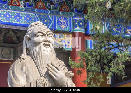 Primo piano della statua di Confucio di fronte al colorato tempio antico con splendidi ornamenti Foto Stock