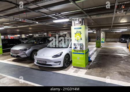 Oxford, Regno Unito - 5 giugno 2024: Ricarica Tesla in un parcheggio sotterraneo pieno di auto con postazioni di ricarica per auto elettriche. Foto Stock