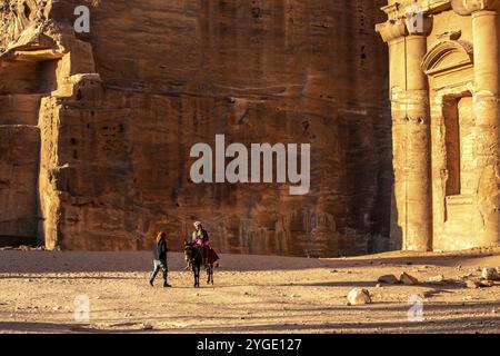 Petra, Giordania, 3 novembre 2022: Persone, asino al monastero di ad Deir nell'antica città, vista panoramica al tramonto, sito patrimonio dell'umanità dell'UNESCO, Asia Foto Stock