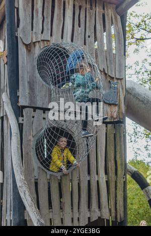 Un bambino sale su una griglia alpina in un parco giochi in una calda giornata estiva. Parco giochi per bambini in un parco pubblico, animazione e ricreazione f Foto Stock