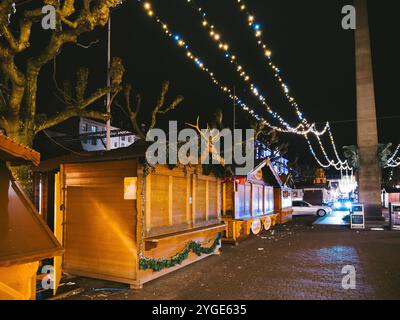 Strasburgo, Francia - 23 dicembre 2024: Bancarelle di legno vuote e luci festive di notte nel mercatino di Natale di Strasburgo, che mettono in mostra l'atmosfera tranquilla dopo l'evento con rifiuti sparsi Foto Stock