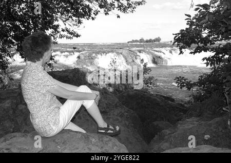 Donna caucasica anziana che si gode un momento di pace mentre si ammira la vista panoramica delle Cascate del Niagara, New York, Stati Uniti. Foto Stock