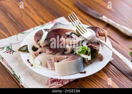 sgombro leggermente salato con cipolle e spezie, in un piatto su un tavolo di legno. Foto Stock