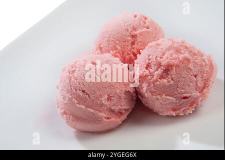 tre cucchiai di gelato alle fragole in un piattino bianco Foto Stock