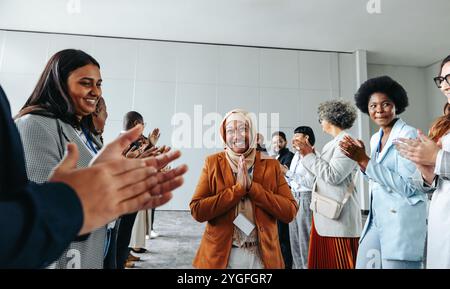 Gruppi diversi di professionisti che applaudono e festeggiano insieme in una riunione d'affari. Un ambiente di lavoro gioioso e collaborativo. Foto Stock