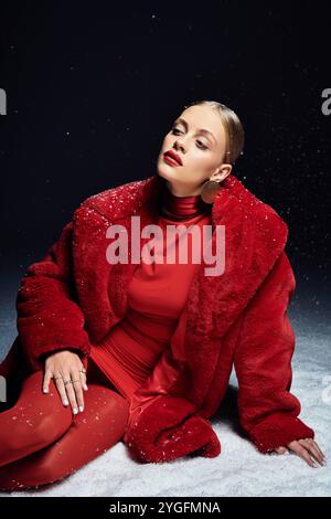 Una bella giovane donna vestita di rosso si posa con cura su uno sfondo innevato. Foto Stock