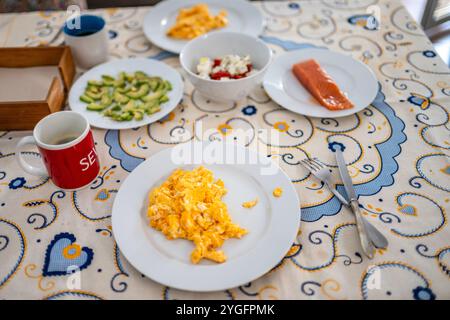 Un delizioso brunch fatto in casa a Siviglia, con uova strapazzate, salmone affumicato, avocado, insalata di pomodoro, e una tazza calda di caffè, creando un rif Foto Stock