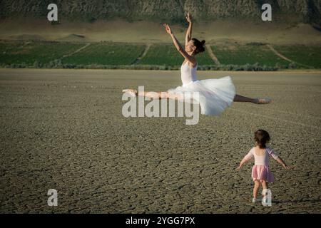 La bambina in abito rosa imita sua madre che danzava balletto sullo sfondo della natura Foto Stock