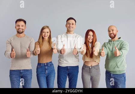 I giovani mostrano pollice su sfondo grigio Foto Stock