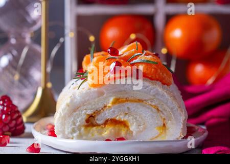 Rotolo di meringa ripieno di mascarpone, crema e marmellata di mandarini, decorato con mandarini e semi di melograno. Foto Stock