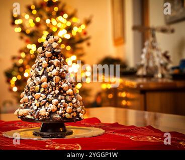 Albero di Natale fatto di cioccolato su sfondo di luci sfocate. Foto Stock