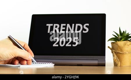 Trend di pianificazione simbolo del nuovo anno 2025. Concept Words Trends 2025 su un bellissimo tablet nero. Splendido sfondo bianco. Mano d'affari. tren. Commerciale Foto Stock