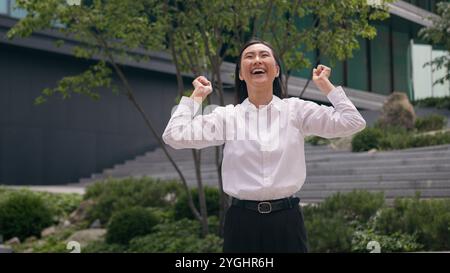 Felice donna asiatica coreana cinese donna d'affari che cammina va stepping ragazza d'affari godere ottenere sorriso celebrare il trasferimento città datore di lavoro in centro Foto Stock
