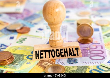 Baviera, Germania - 7 novembre 2024: Stipendio netto, scritto su un francobollo accanto alle banconote e alle banconote in euro. Simbolo degli stipendi e delle retribuzioni pagate al dipendente. FOTOMONTAGGIO *** Nettogether, steht auf einem Stempel neben Geld-Scheinen und Euro-Banknoten. Symbol für Gehälter und Gehaltszahlungen, die netto ausgezahlt werden an den Arbeitnehmer. FOTOMONTAGE Foto Stock