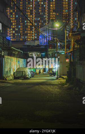 Balikpapan, Indonesia - 3 settembre 2024. un vicolo stretto in una città di notte. illuminato da lampioni. Ci sono delle auto parcheggiate sul lato della t Foto Stock