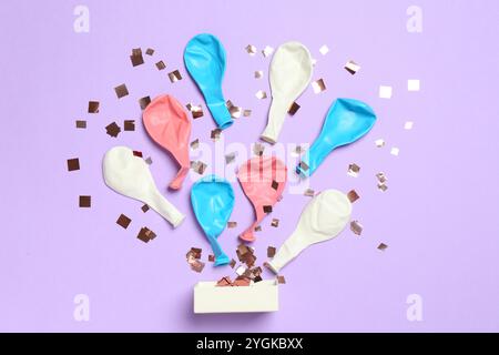 Coriandoli lucenti e palloncini sgonfiati che volano fuori da una piccola scatola su sfondo viola, piatto Foto Stock
