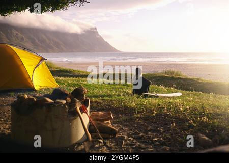 Donna, oceano e campeggio con tavola da surf per avventure, pause e vacanze in Australia. Donna, spiaggia e relax per hobby o sport con Foto Stock