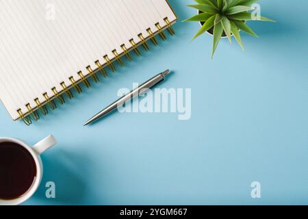 Vista dall'alto di notebook, bicchieri, caffè e penna a sfera su sfondo blu Foto Stock