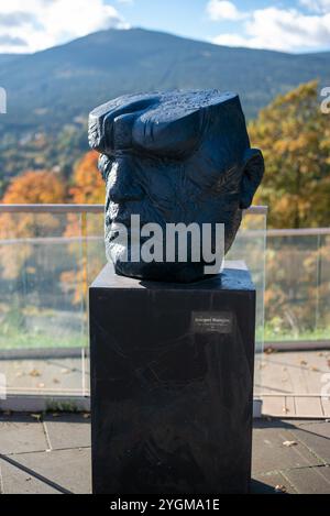 La scultura della testa di Grzegorz Niemyski si trova in primo piano a Szklarska Poręba, sullo sfondo di montagne nebbiose, che fondono arte e natura" Foto Stock