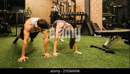 Due persone si allenano in una palestra moderna, esercitano pesi su un pavimento in erba verde. Foto Stock