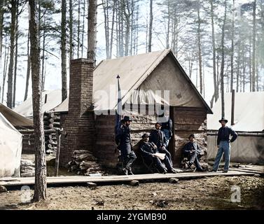 Ufficiali di fronte ai quartieri invernali al quartier generale dell'Armata del Potomac, Brandy Station, Virginia. Fotografia dal principale teatro orientale della guerra, dicembre 1863-aprile 1864. Creato nel mese di febbraio 1864. Situata sulla Orange and Alexandria Railroad, Brandy Station servì come deposito di rifornimenti e passeggeri dell'Union Army of the Potomac durante il loro accampamento invernale del 1863-1864 in quest'area. Qui a Brandy Station, tra il trambusto di carico e scarico di rifornimenti e personale, i soldati potrebbero farsi fotografare per 1,50 dollari o spendere i loro soldi per qualsiasi altro oggetto Foto Stock