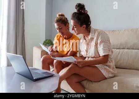 Due donne coppia che rivede le bollette e i documenti finanziari insieme a casa Foto Stock