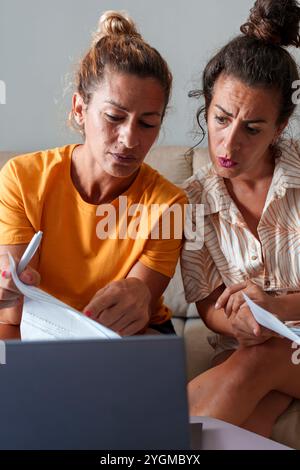 Due donne coppia che rivede le bollette e i documenti finanziari insieme a casa Foto Stock