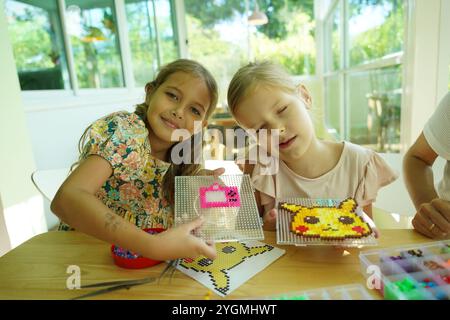 L'insegnante in officina ha messo in tecnica due ragazze come assemblare un mosaico termico Foto Stock