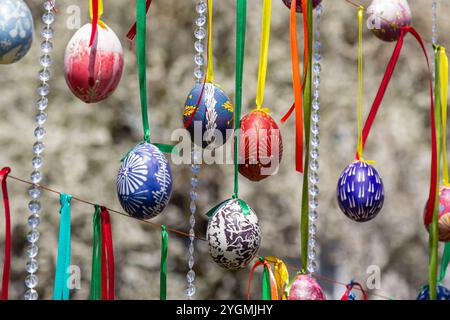 Le uova dipinte pendono dai rami dell'albero di Pasqua. Il fuoco è su un uovo giallo dipinto dai bambini a mano. Foto di alta qualità Foto Stock