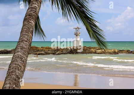 Ammira il faro su un'isola rocciosa in un mare attraverso le foglie di palma Foto Stock