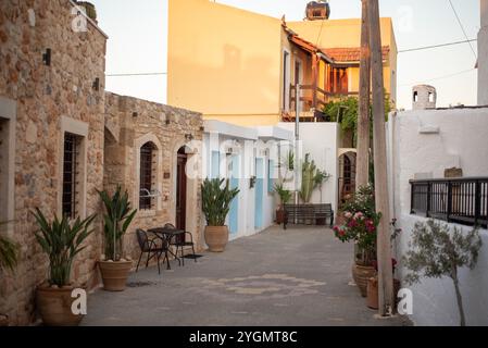 Strette strade greche a Hersonissos, Creta, Grecia, fiancheggiate da affascinanti edifici imbiancati, fiori colorati e vivaci negozi locali, che trasudano il carattere Foto Stock